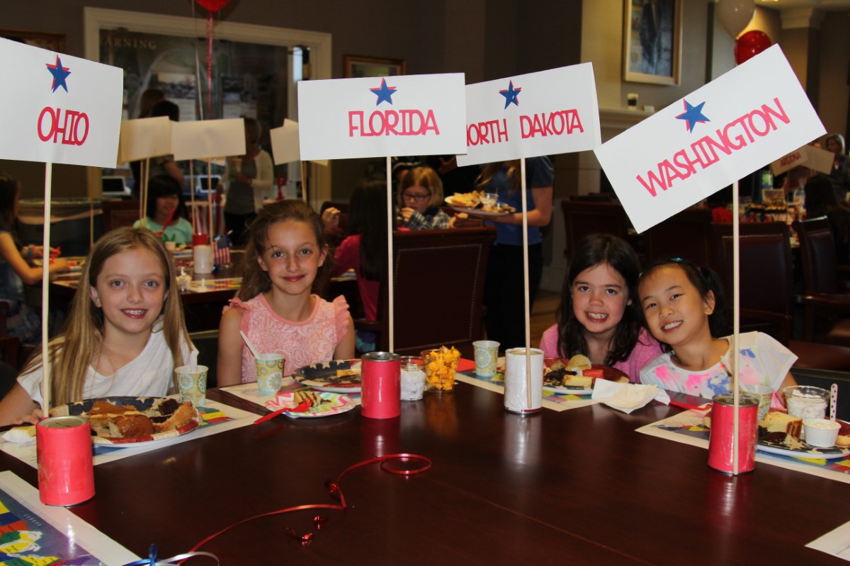 Students sit at the table with signs indicating their states