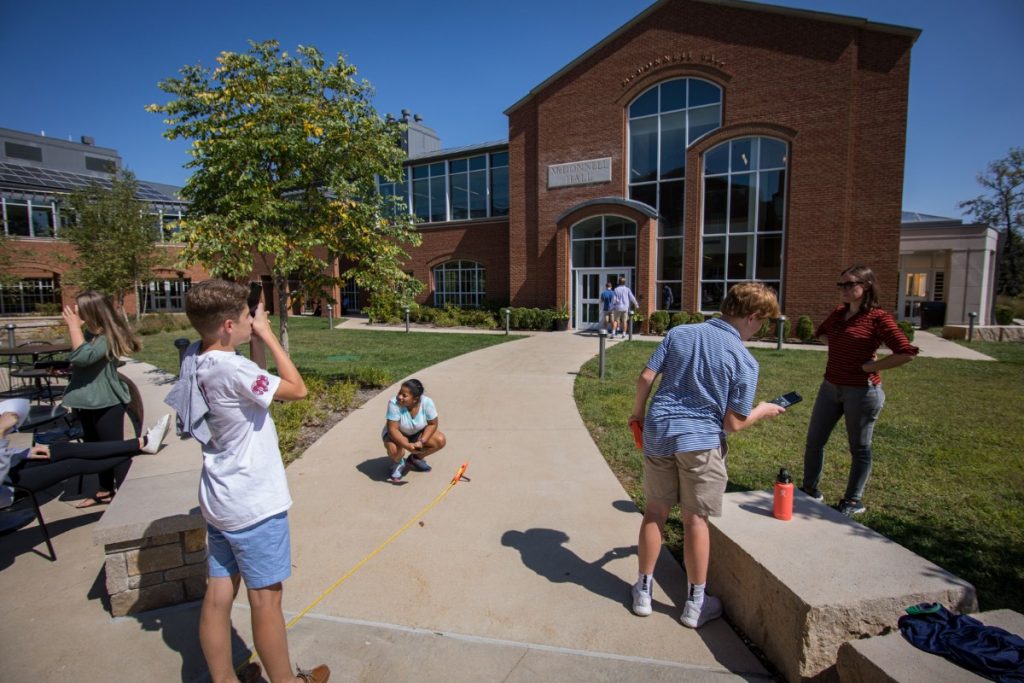 Students doing math in the courtyard to determine height of McDonnell Hall