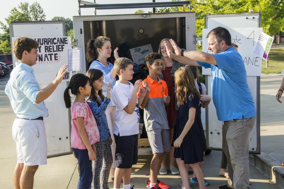 Students gather around and high five to celebrate backpacks for hurricanes Harvey and Irma relief donation drive