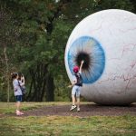 Students standing in front of a giant eyeball sculpture at Laumeier Sculpture Park